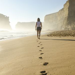 woman walking alone on beach towards water